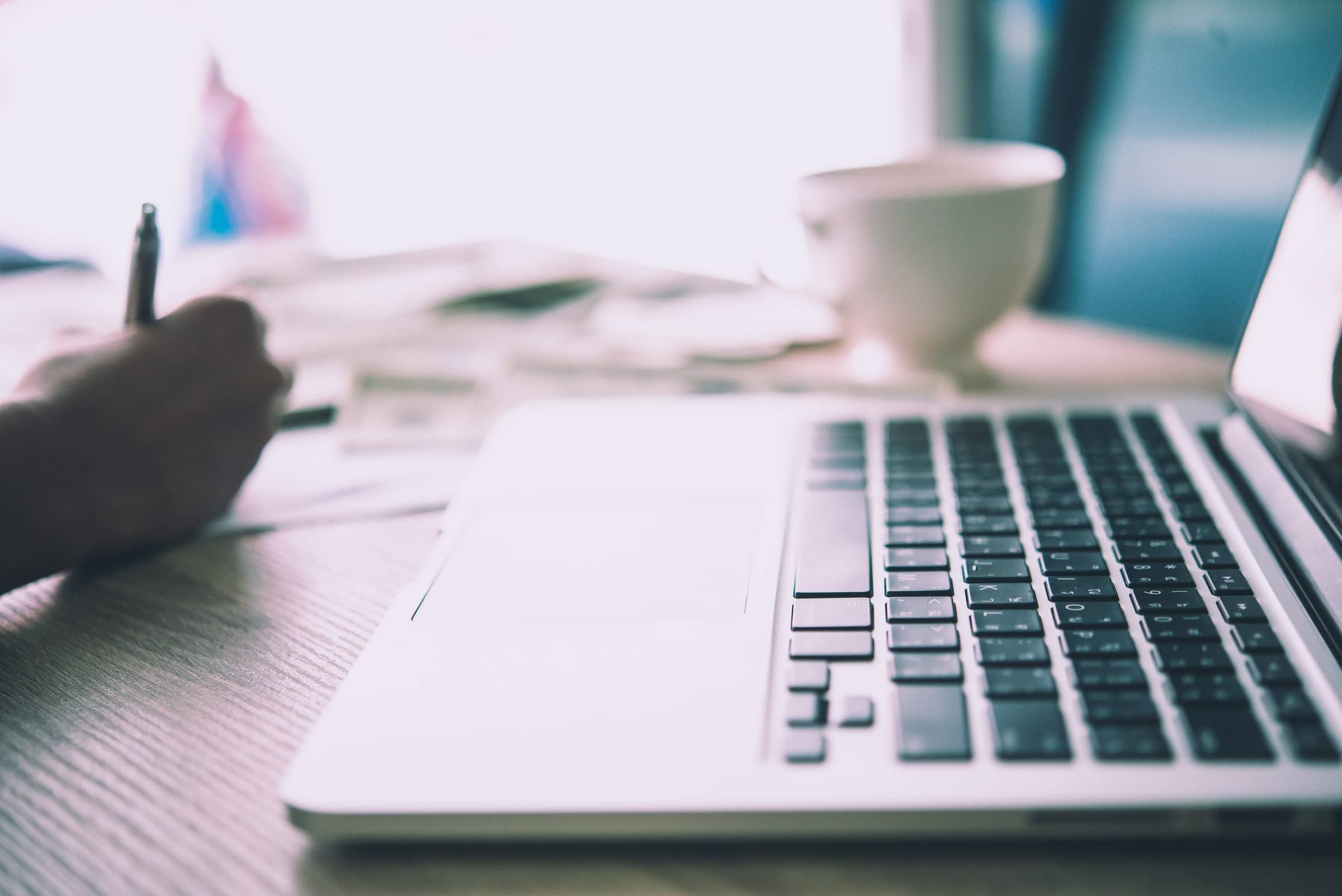Writer taking notes beside a laptop