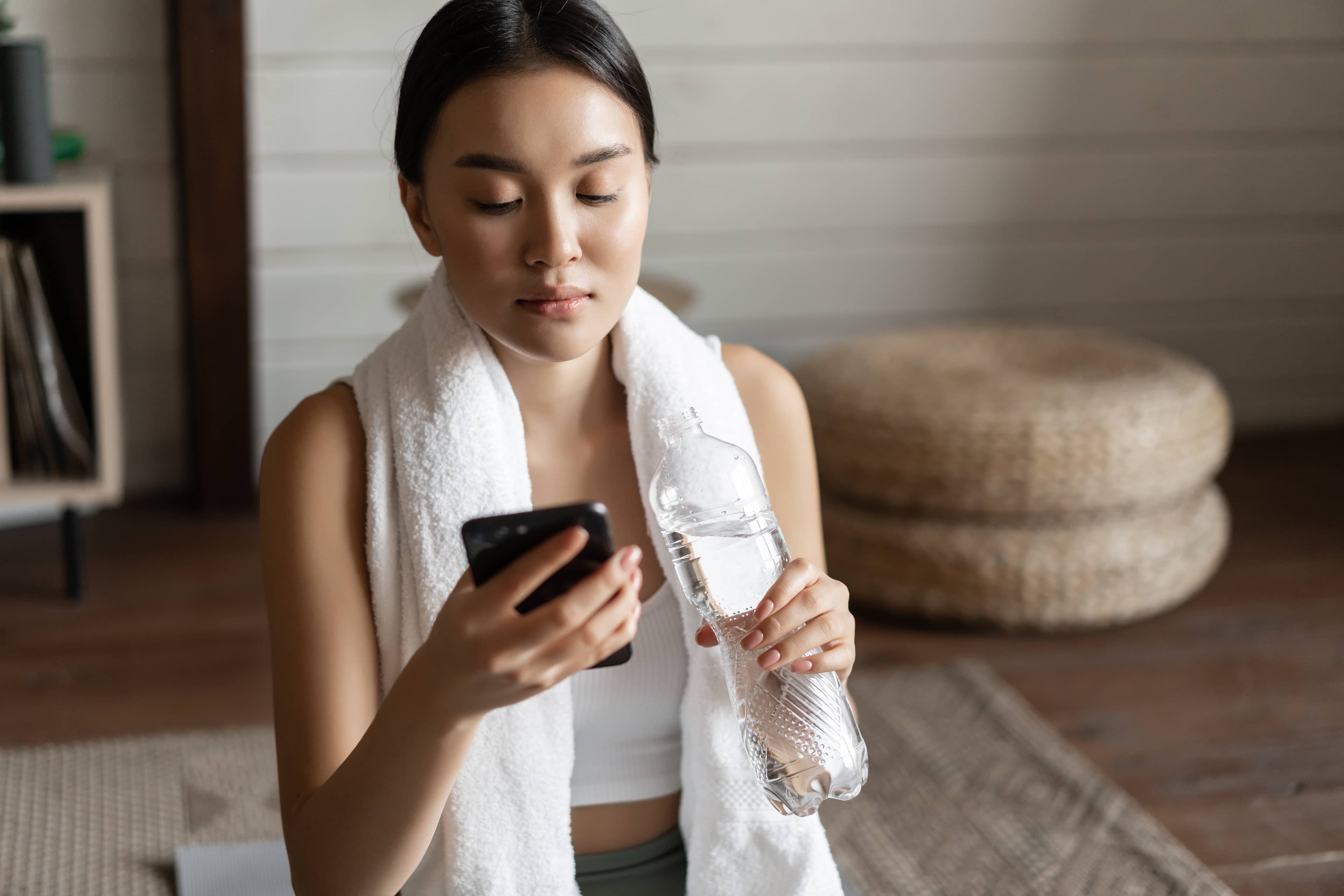Woman after a workout using her phone to book a massage