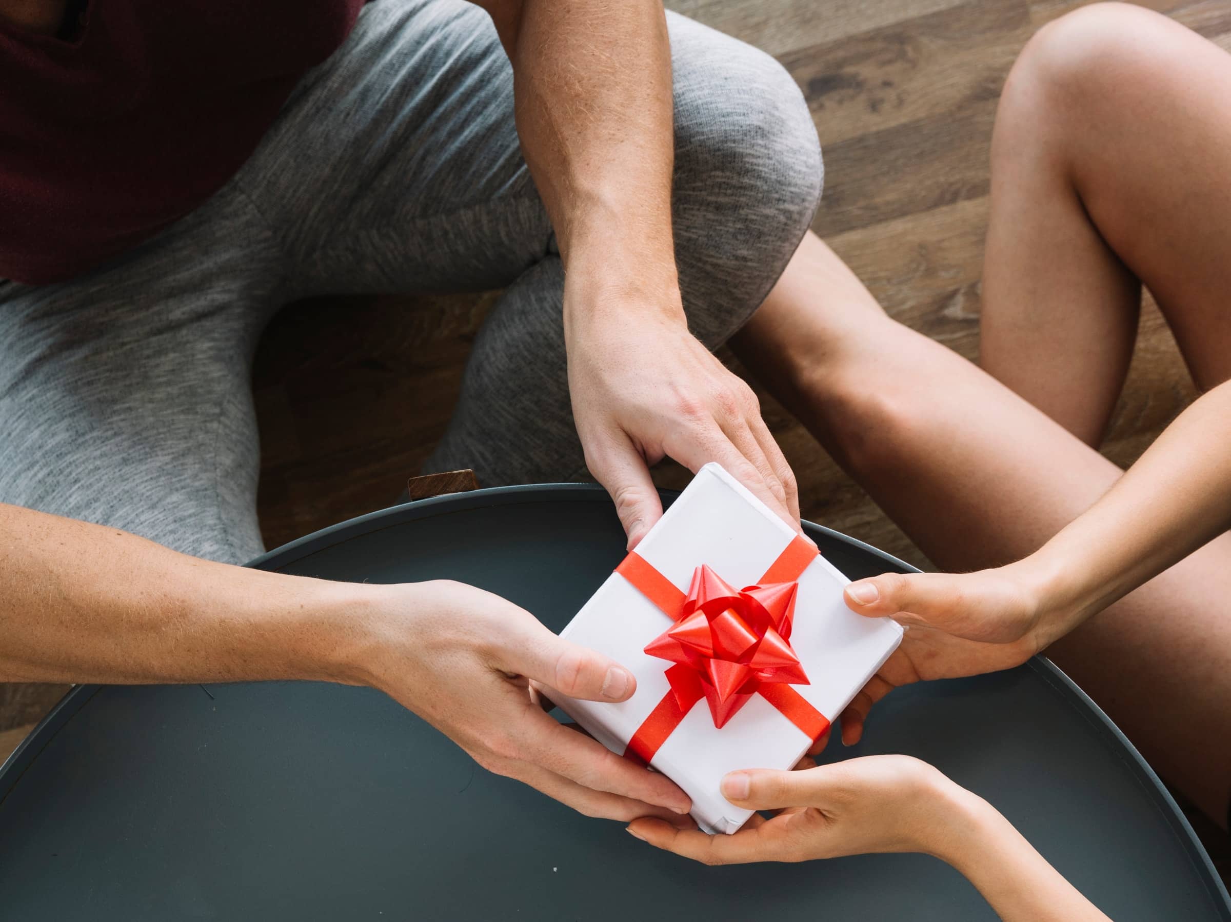 Hands passing a small wrapped gift box